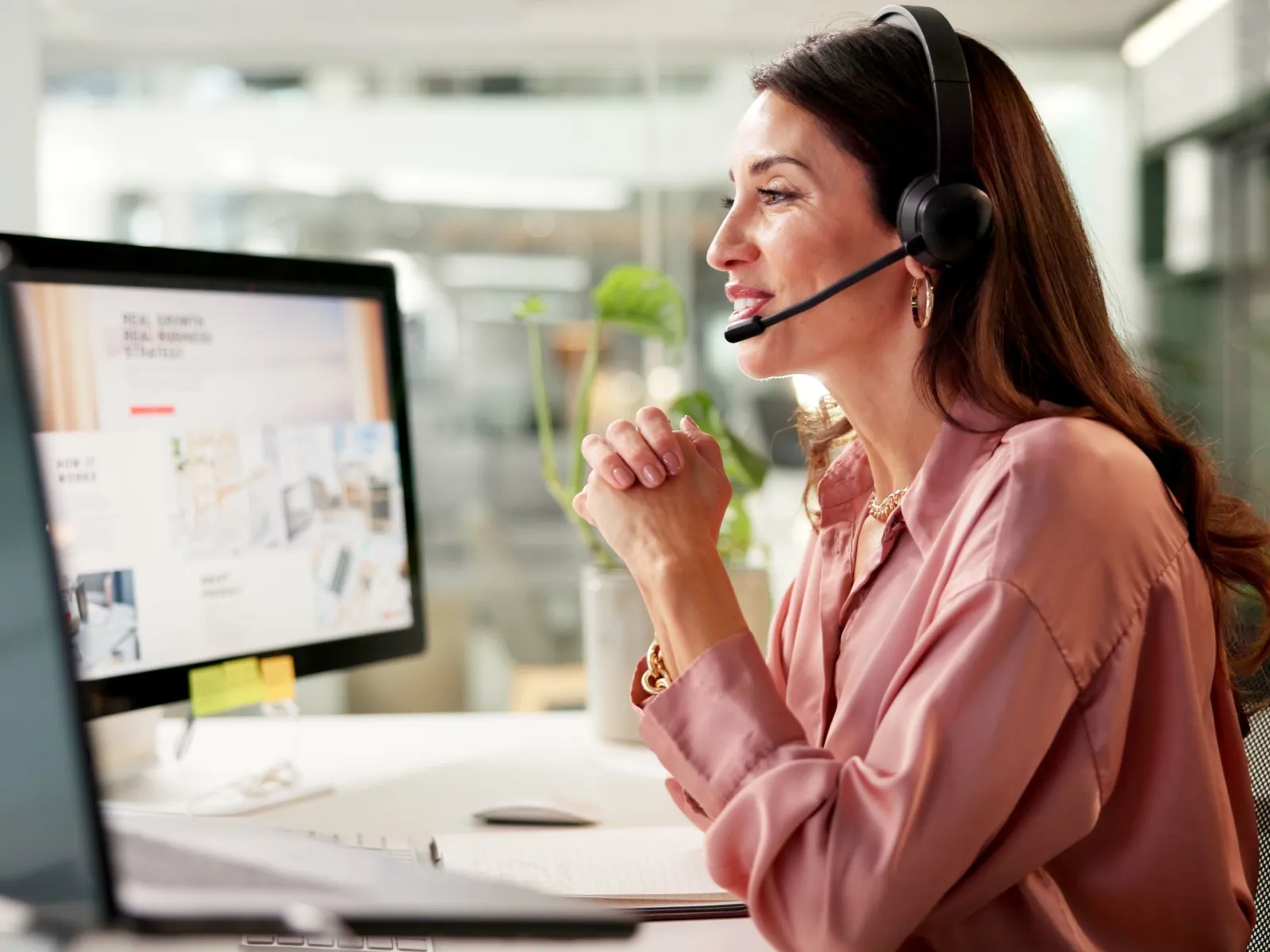 a woman wearing headphones and sitting at a desk with a computer