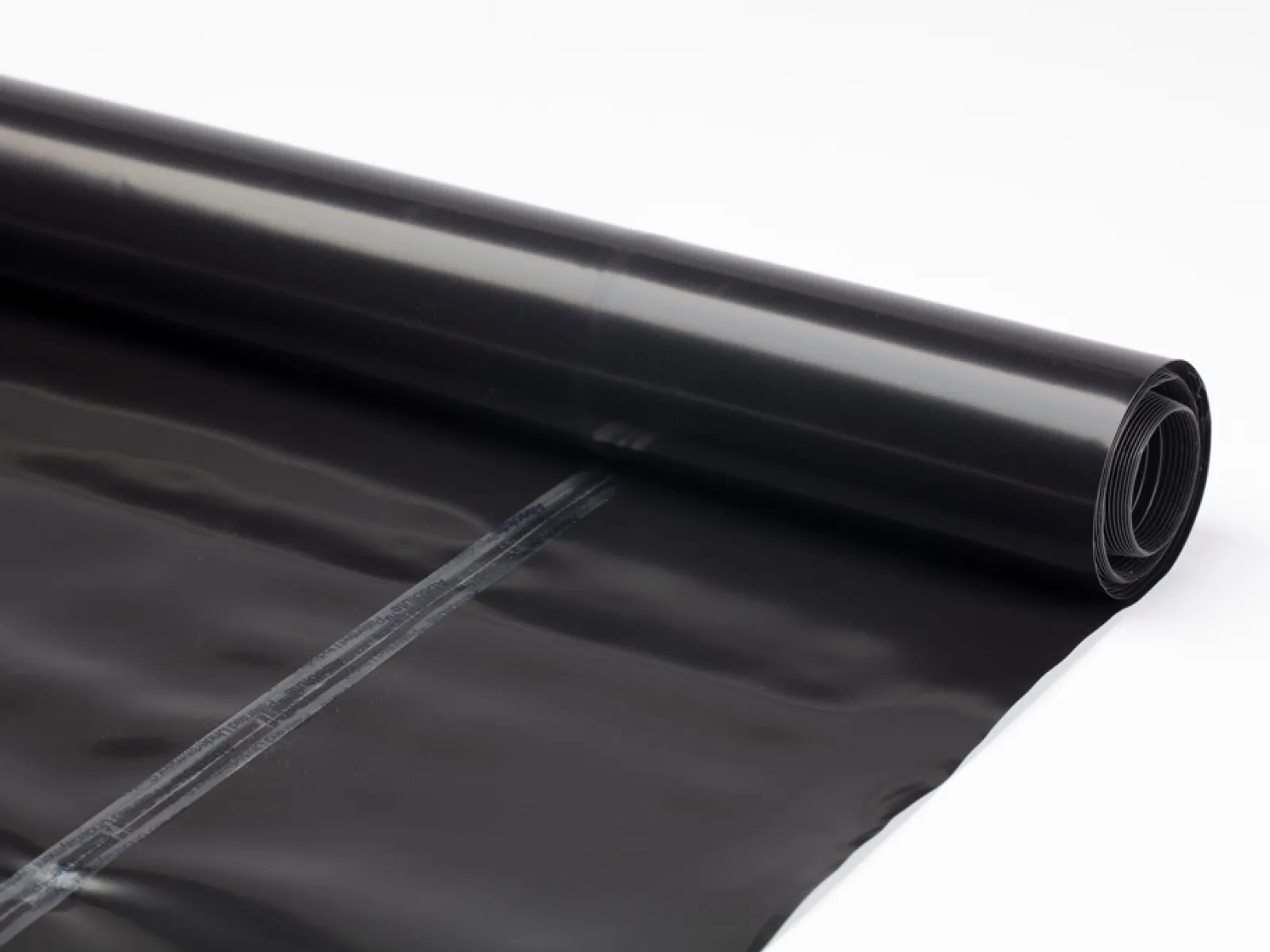 Roll of black plastic trash bags partially unrolled on white background with visible seams.