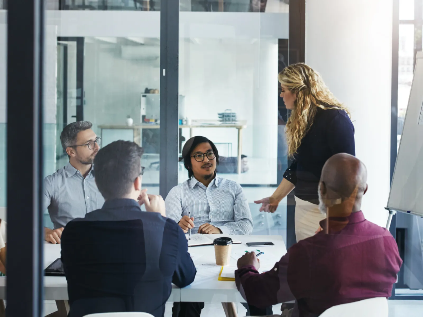 A diverse team in a meeting discussing ideas with a presenter at a modern office space.