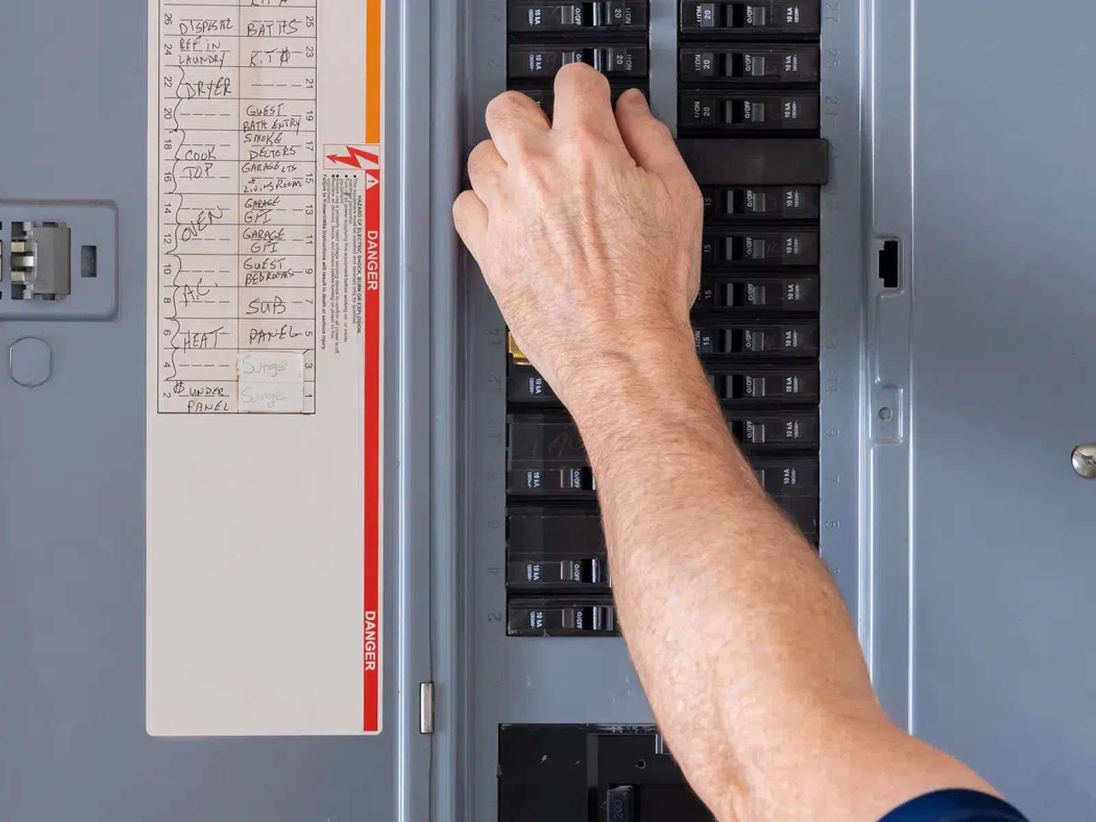 Person turning off a circuit breaker switch inside an electrical panel for home safety or maintenance.