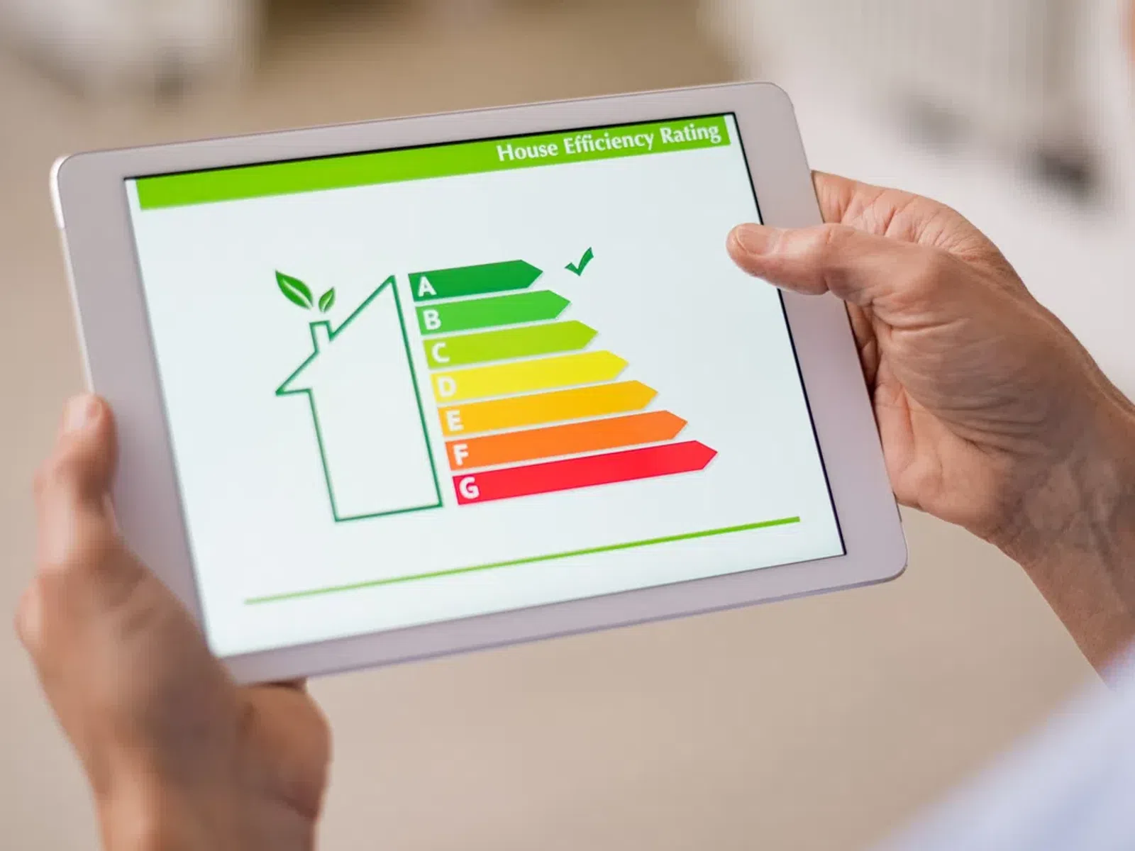 Person holding tablet displaying house energy efficiency rating chart from A to G with green check mark on A.