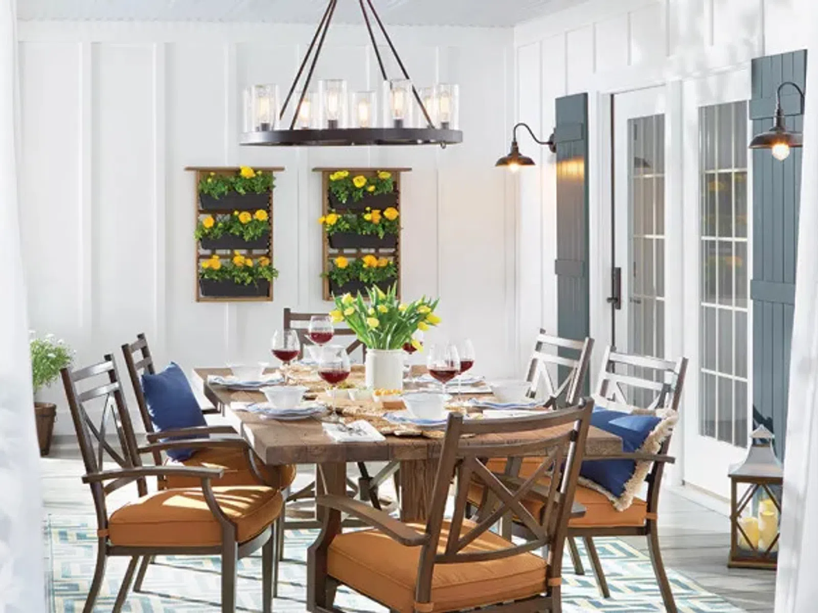 Bright dining room with wooden table, cushioned chairs, wall planters, and modern chandelier with glass lights.