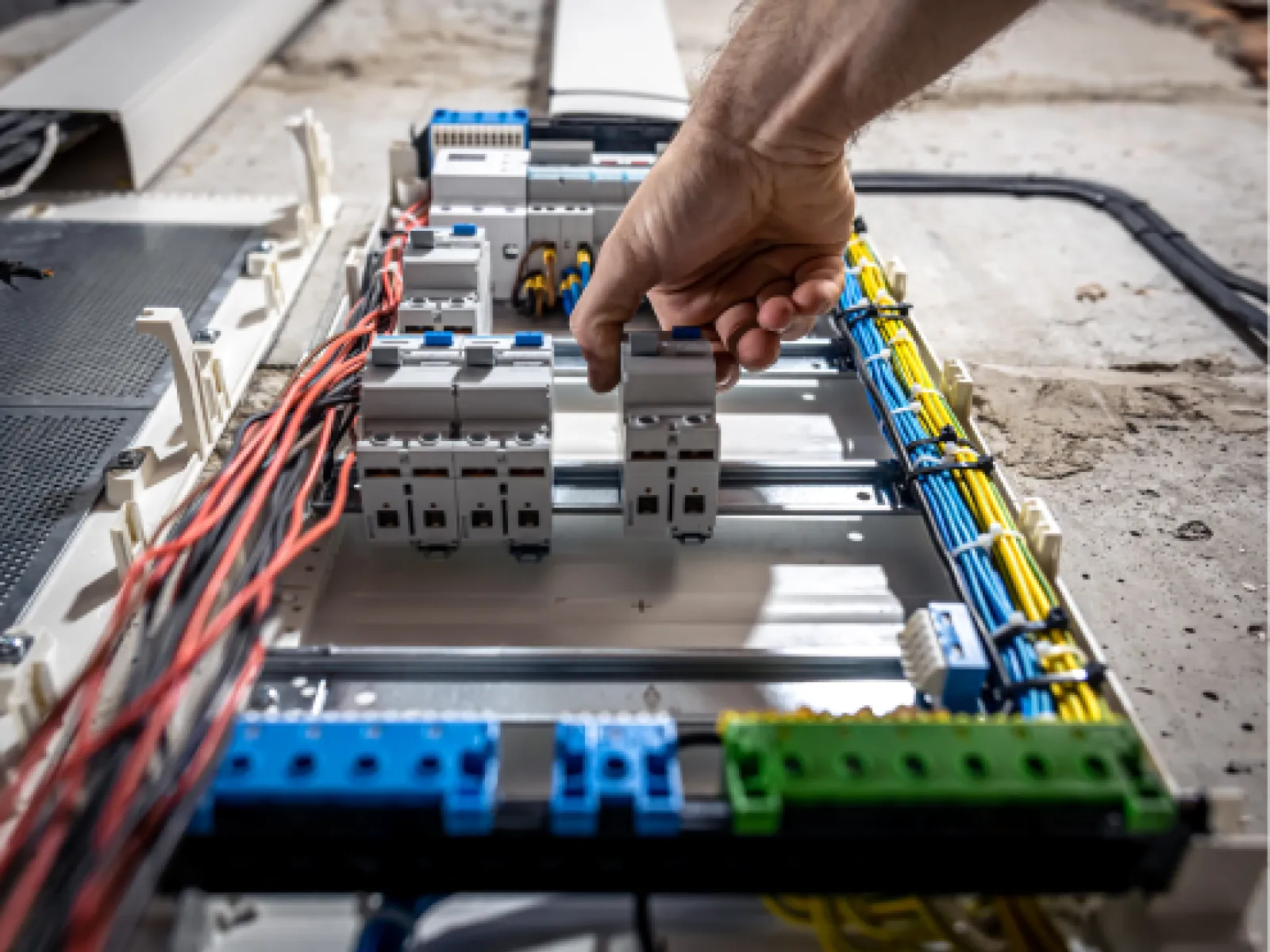 Electrician adjusting circuit breakers inside a modern electrical panel with organized wiring and components