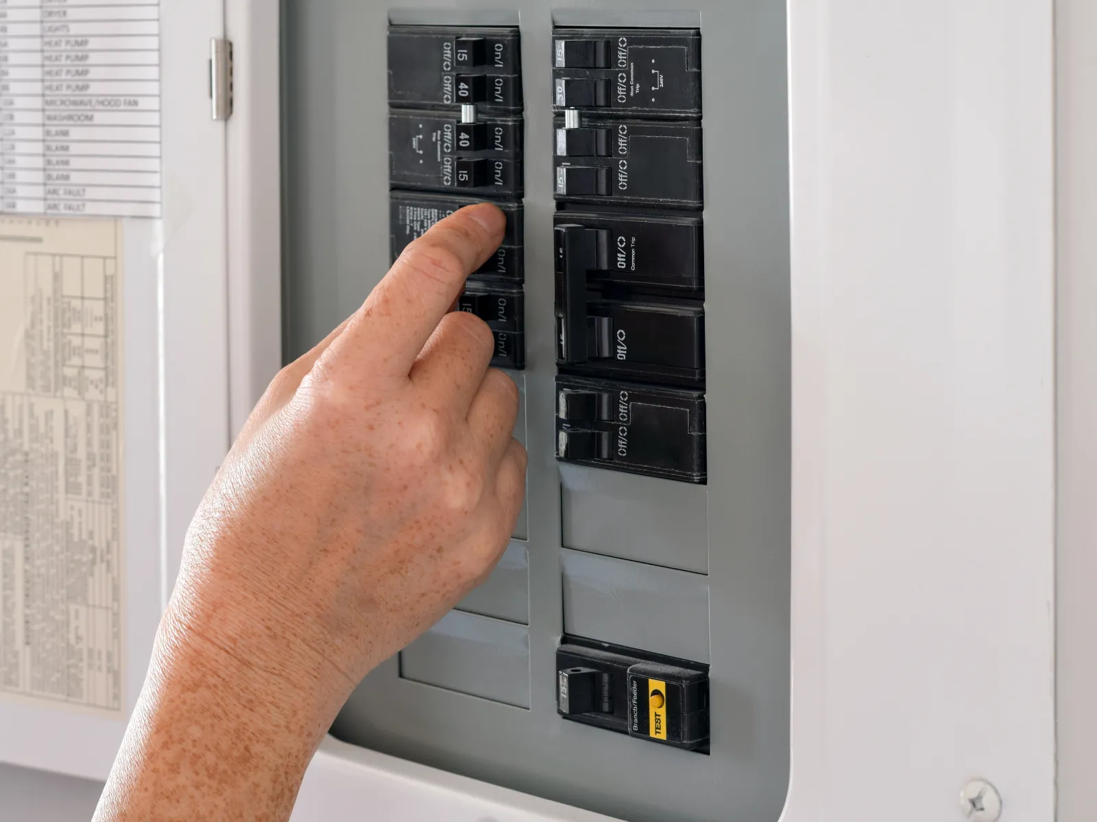 Electrician in blue shirt working on an electrical panel inside a wooden-framed building.