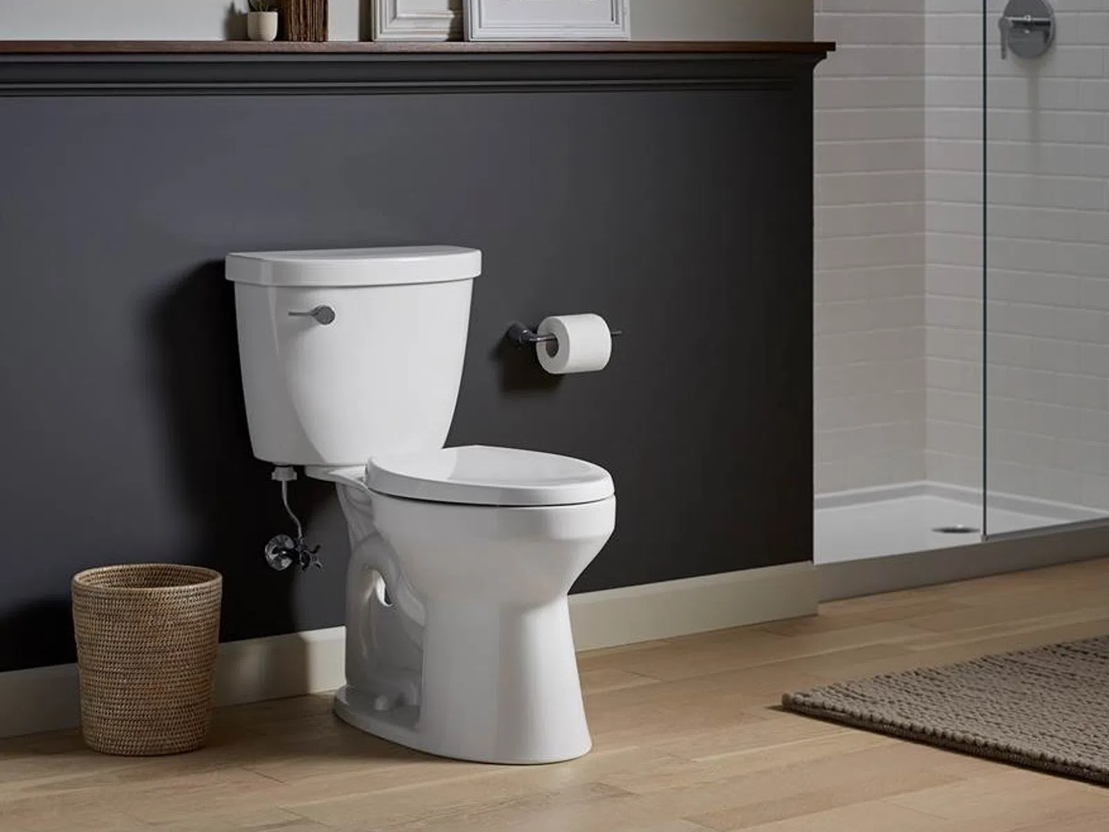 Modern white toilet with a wicker basket and wall-mounted toilet paper holder in a stylish bathroom.