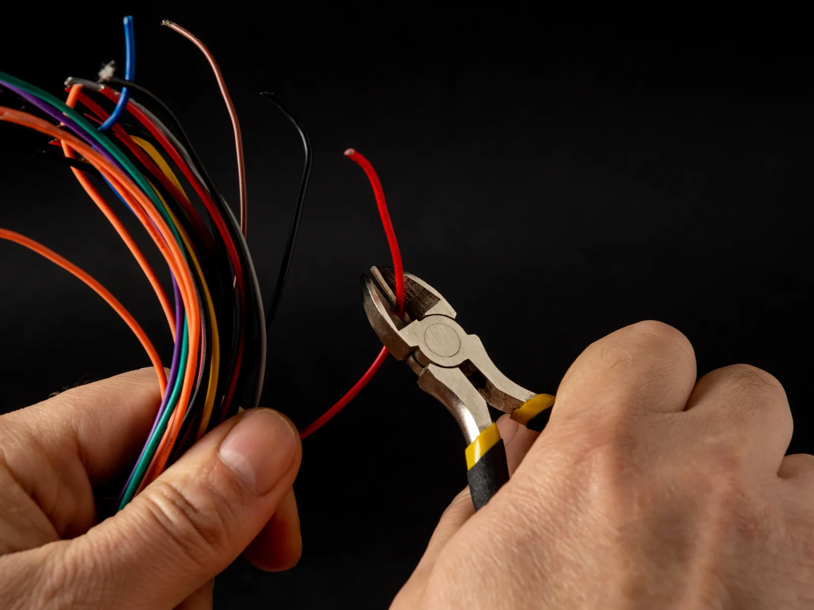 Electrician holding a large coil of black wire inside a building under construction with exposed brick walls.