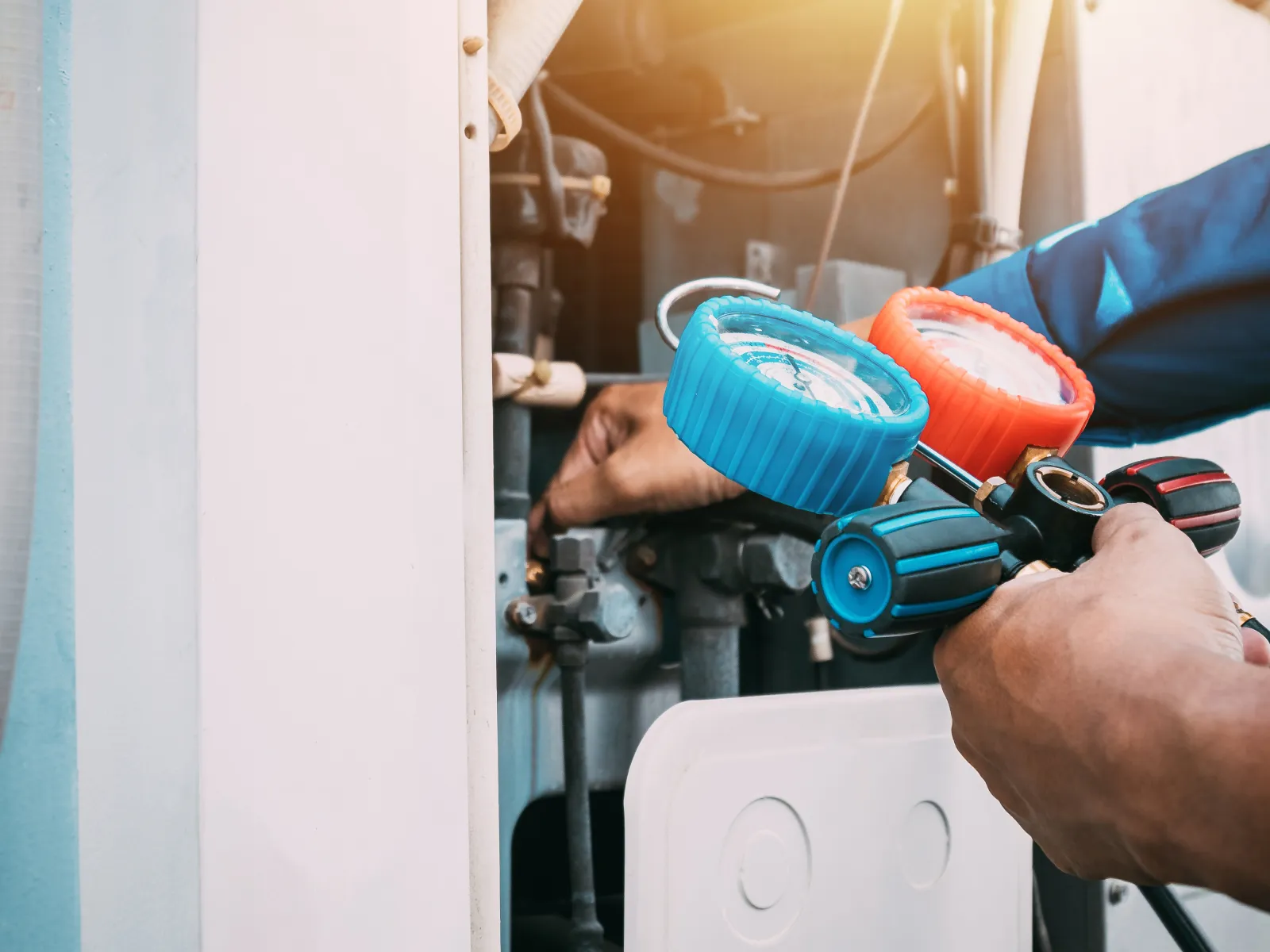 Technician using HVAC gauges to check air conditioning system pressure during maintenance work