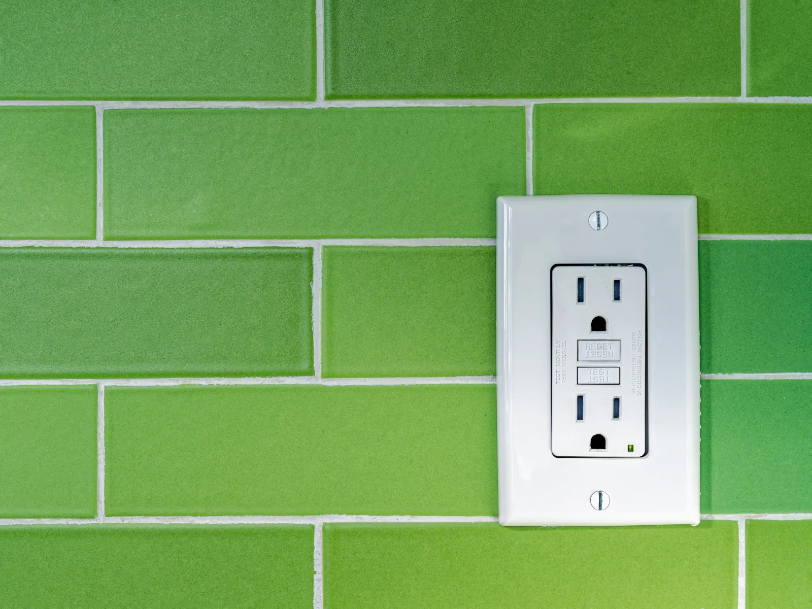 Three white electrical outlets placed on a wooden surface with a blurred background.