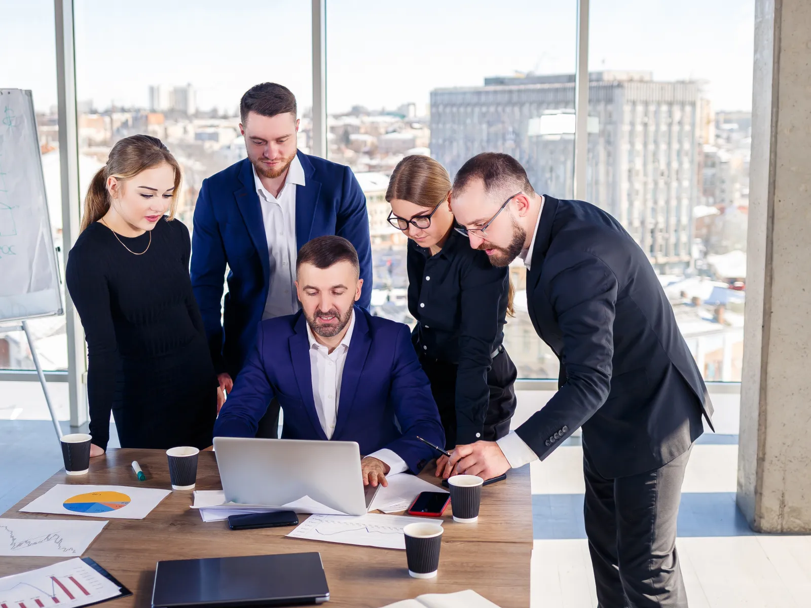 a group of people standing around a table with a laptop