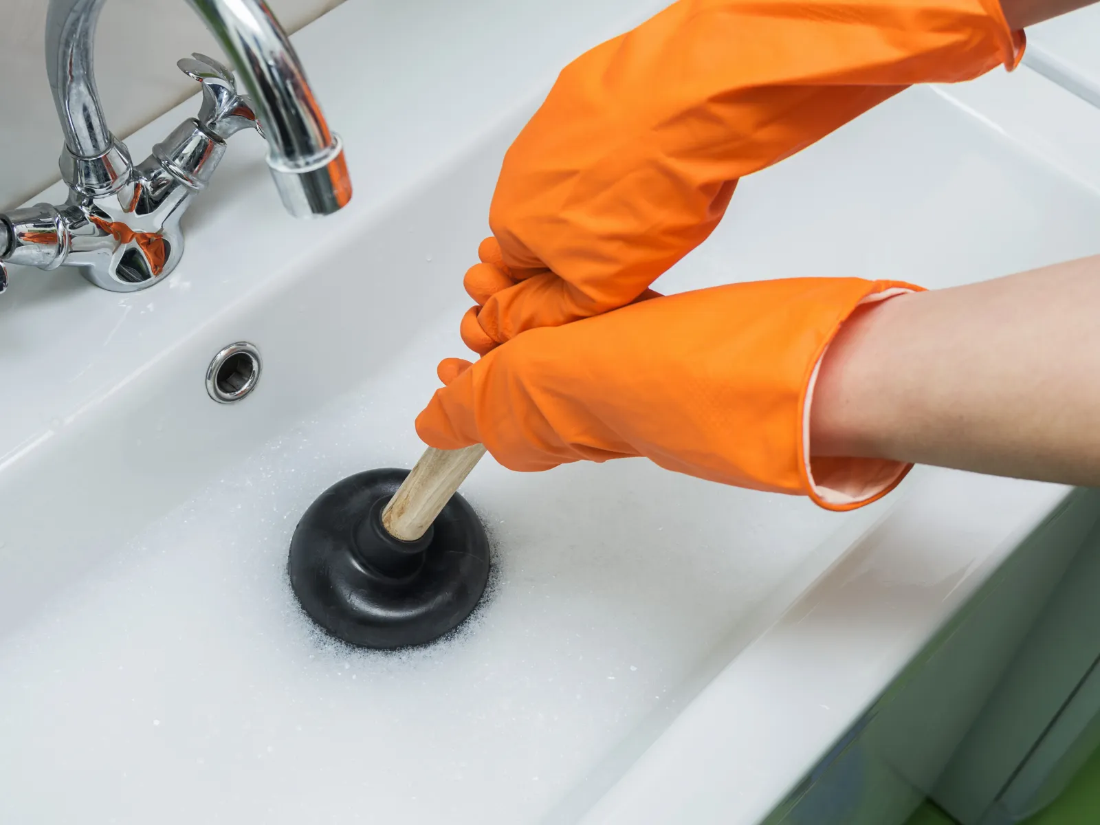 a person's hand holding a small metal object in a sink