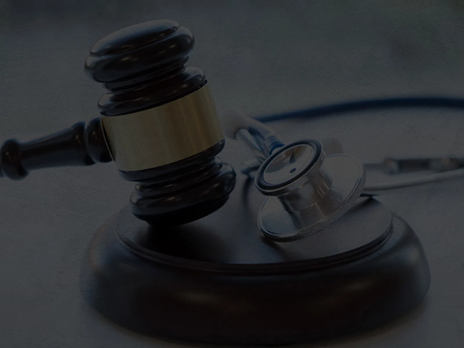Judge's gavel resting on sound block next to a stethoscope on a gray surface symbolizing medical law.
