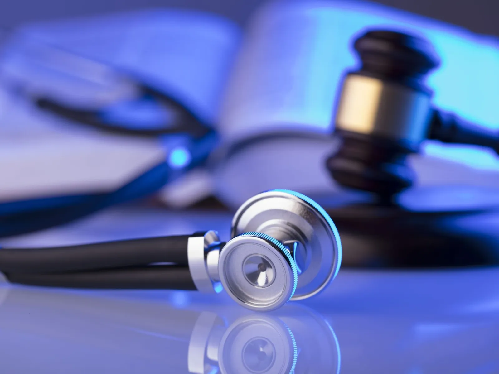 Close-up of a stethoscope, a gavel, and an open book representing medical law and healthcare justice.