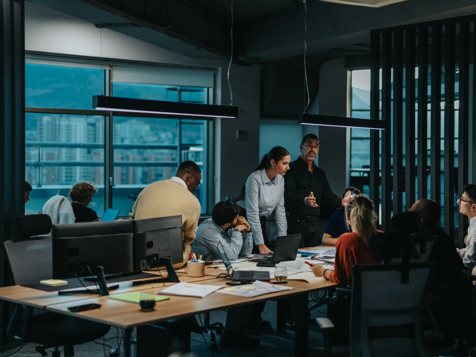 Team of professionals collaborating in a modern office conference room with laptops and documents.