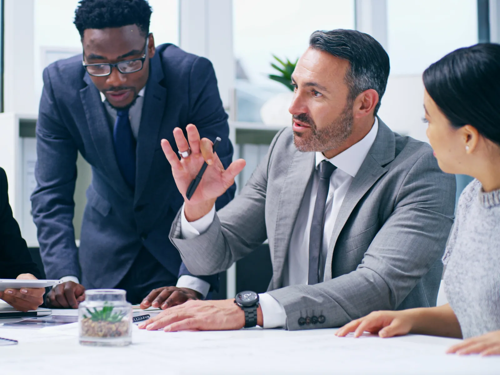Team of diverse professionals collaborating and discussing a project around a conference table in a modern office.