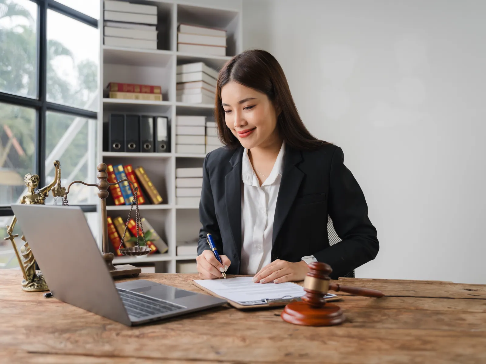 a person sitting at a table with a laptop and a pen