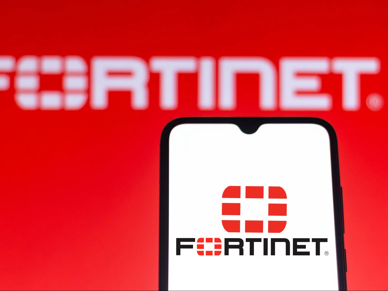 Fortinet logo displayed on a smartphone with a red background featuring the brand name.