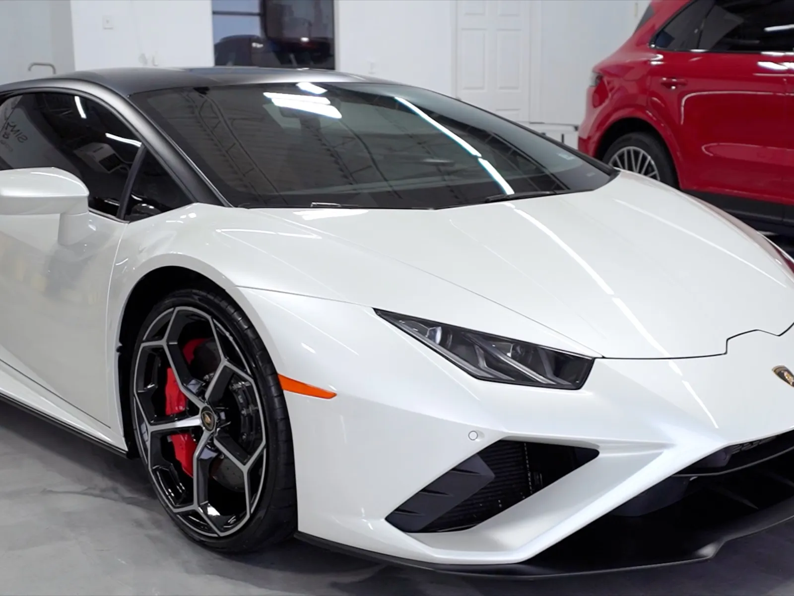 Sleek white Lamborghini sports car parked indoors with glossy finish and black-tinted windows.