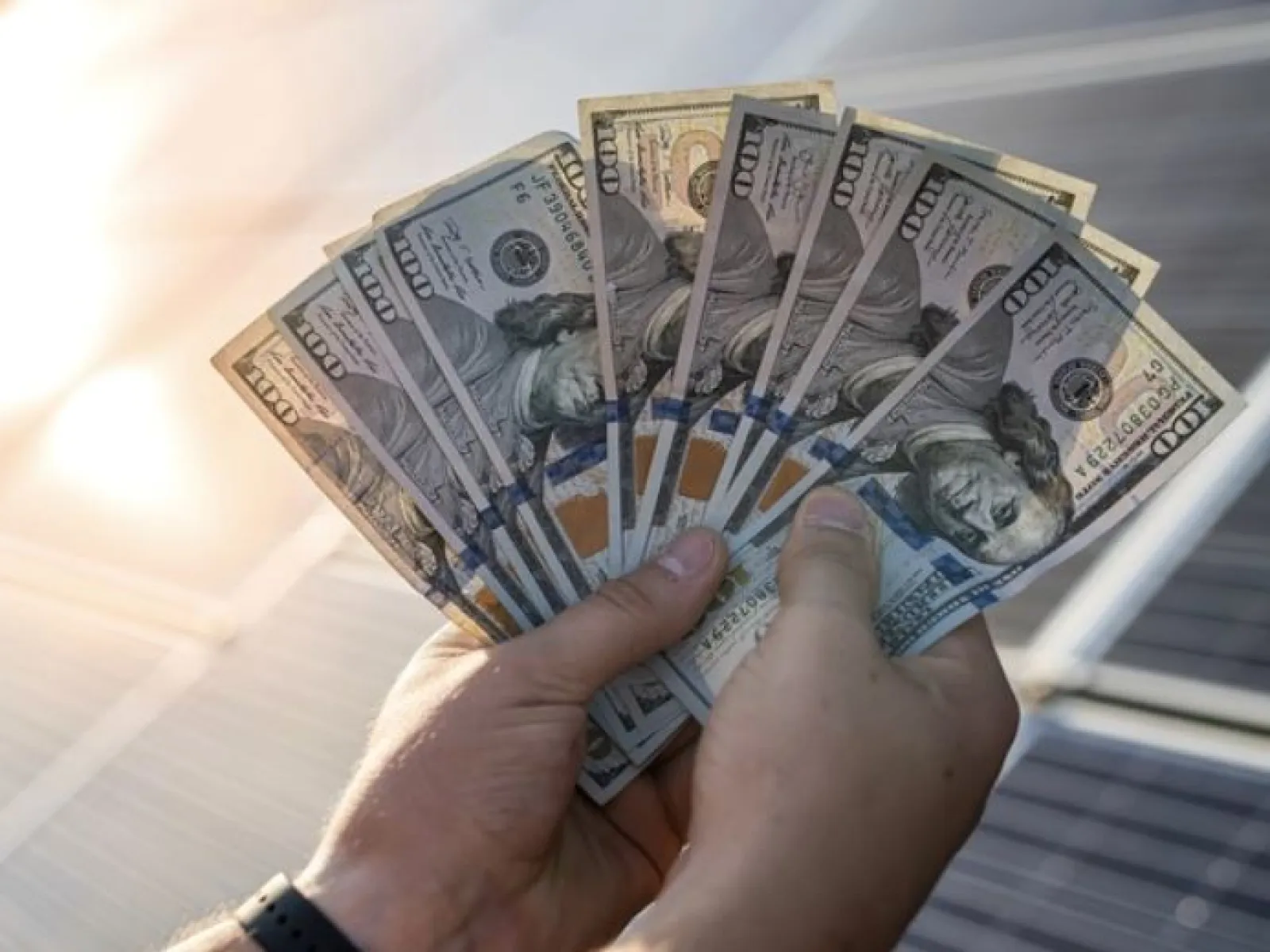 a hand holding a stack of paper money