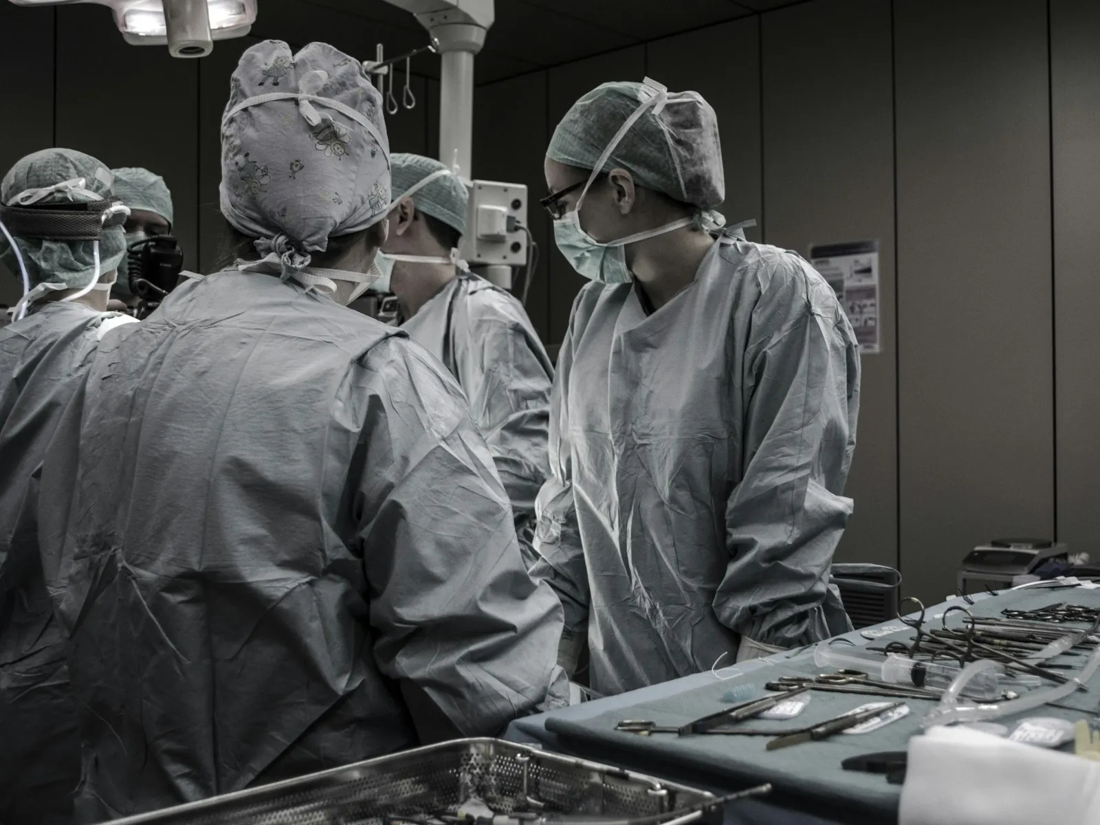 Medical team of surgeons in scrubs performing a surgery in an operating room with surgical instruments nearby