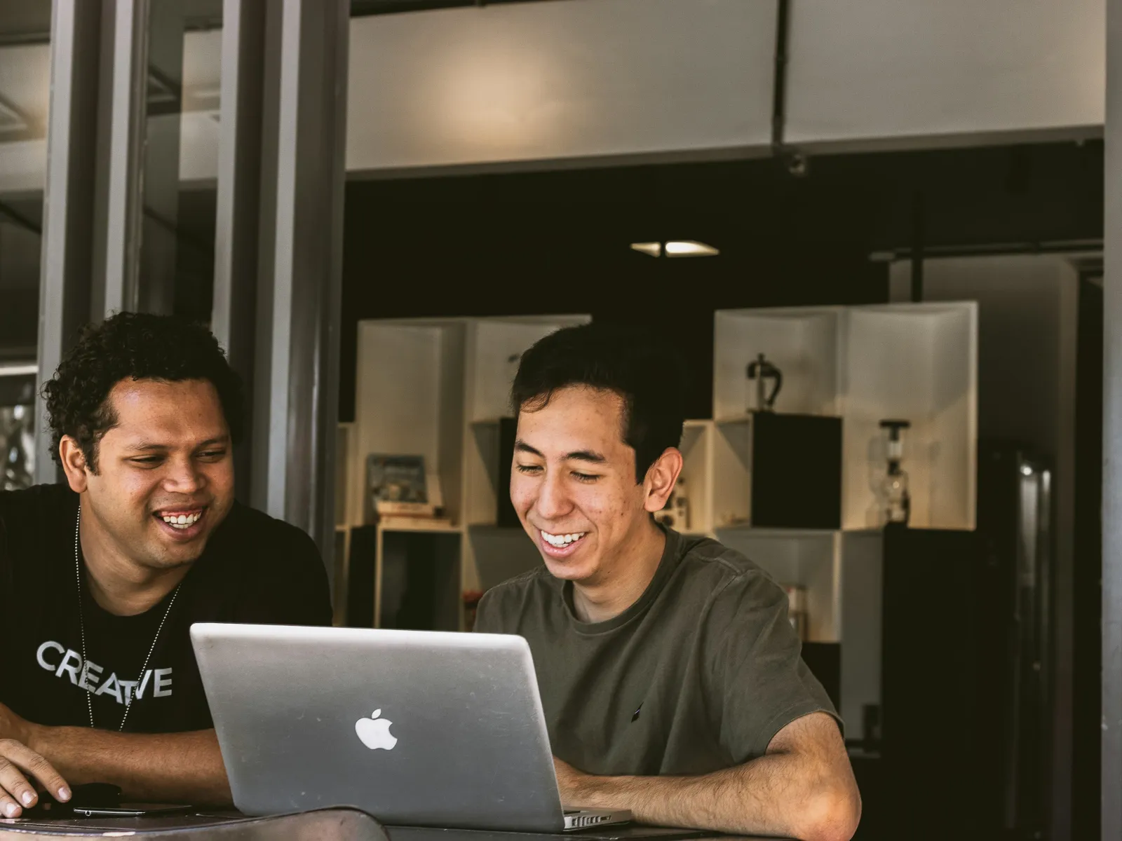 a couple of men smiling at a laptop