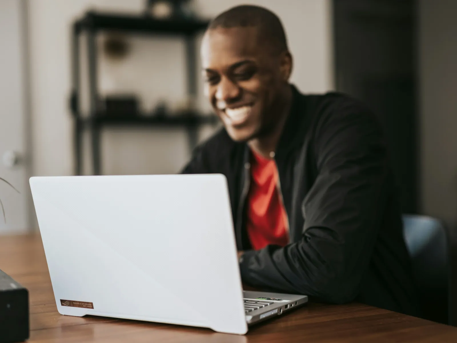 a man smiling and looking at a laptop