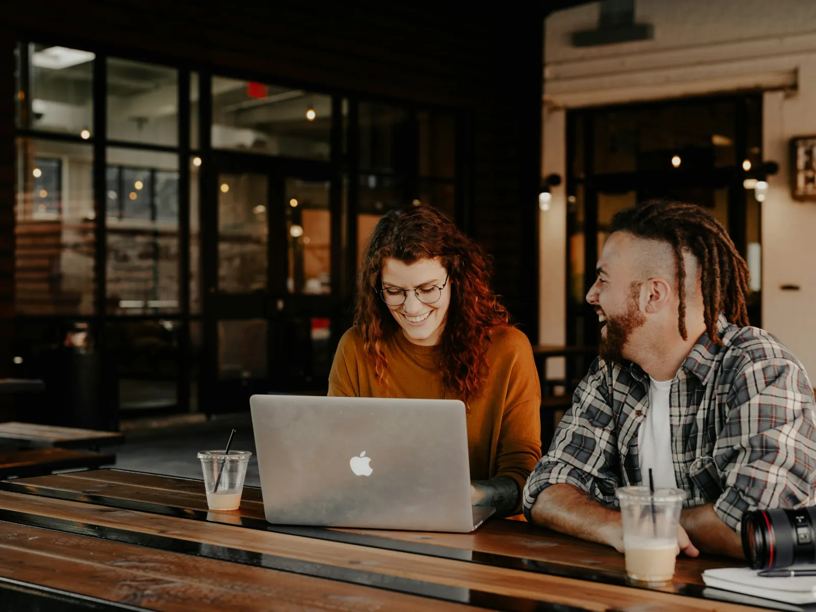 a man and a woman sitting at a table looking at a laptop