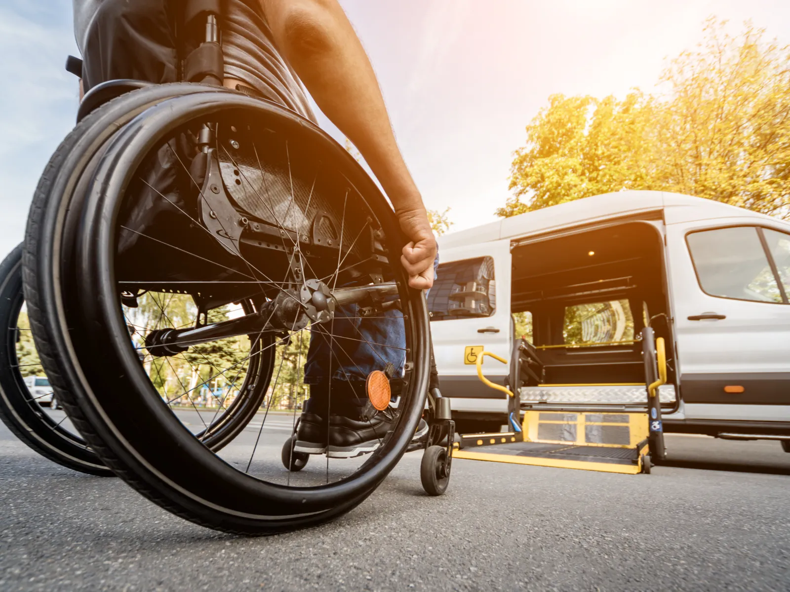 Person in wheelchair approaching accessible van with ramp on sunny day outdoors