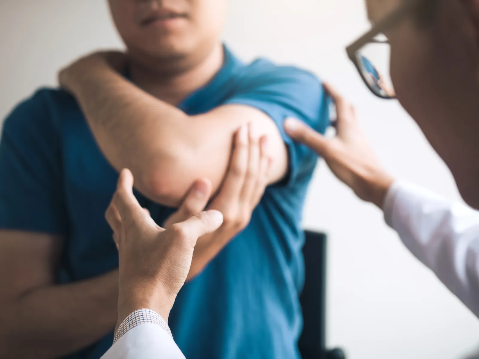 Doctor examining patient's elbow pain during medical consultation for joint or muscle issues.