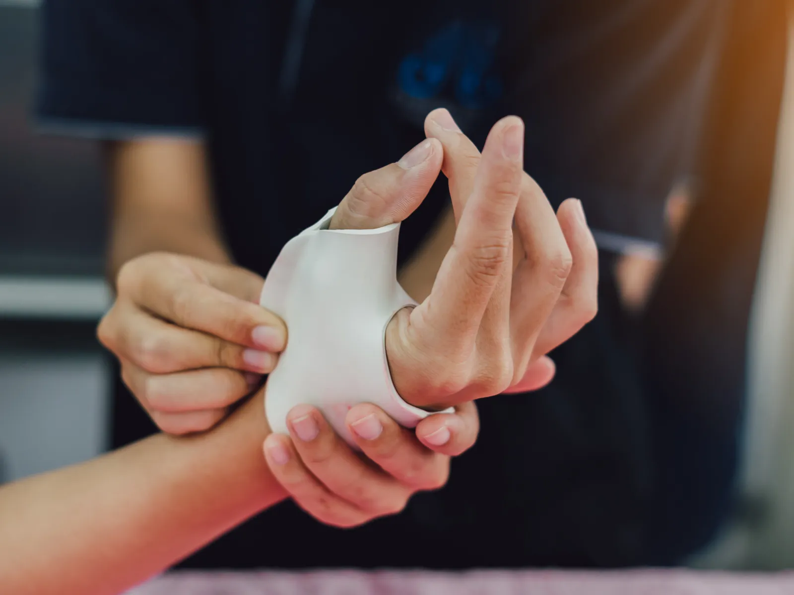Close-up of a person applying a wrist brace to another person's hand for support and injury prevention.