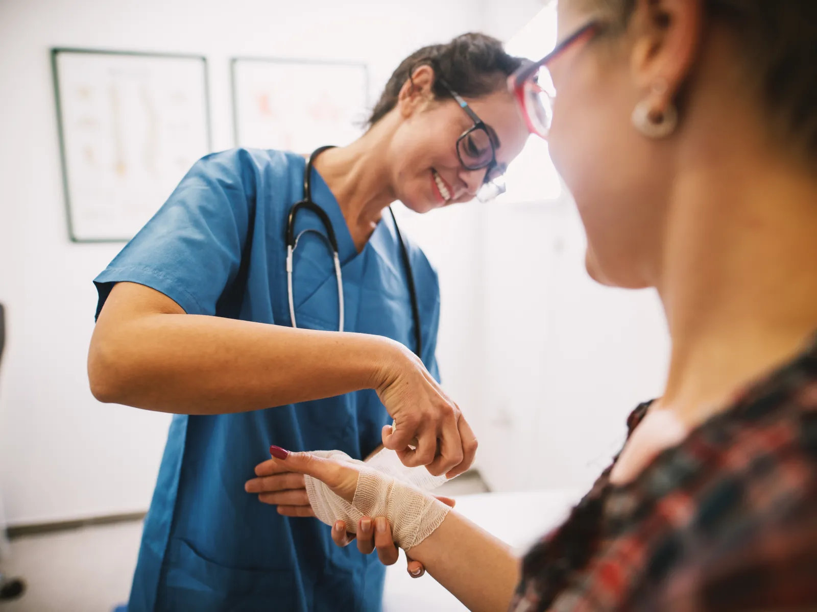Healthcare professional wrapping a bandage on a patient's hand in a medical clinic with a smile