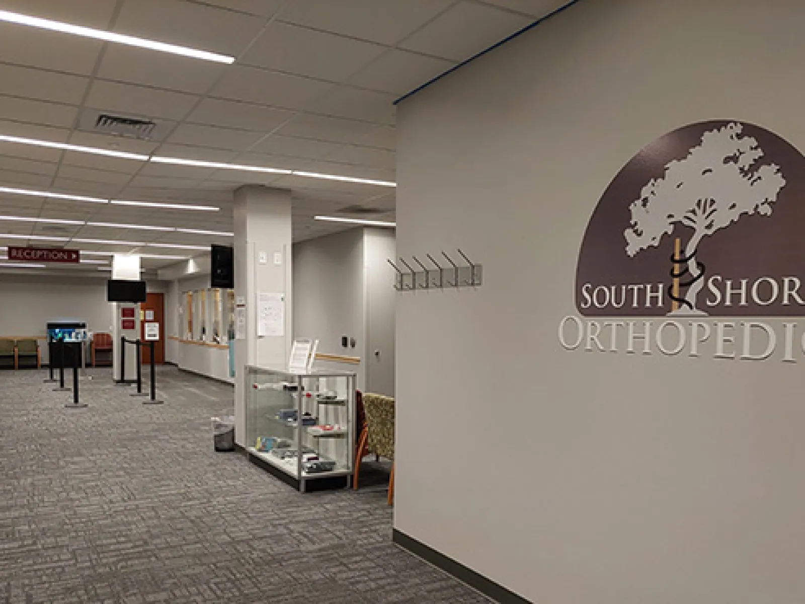Modern waiting area in South Shore Orthopedics clinic with seating, reception sign, and logo on the wall.
