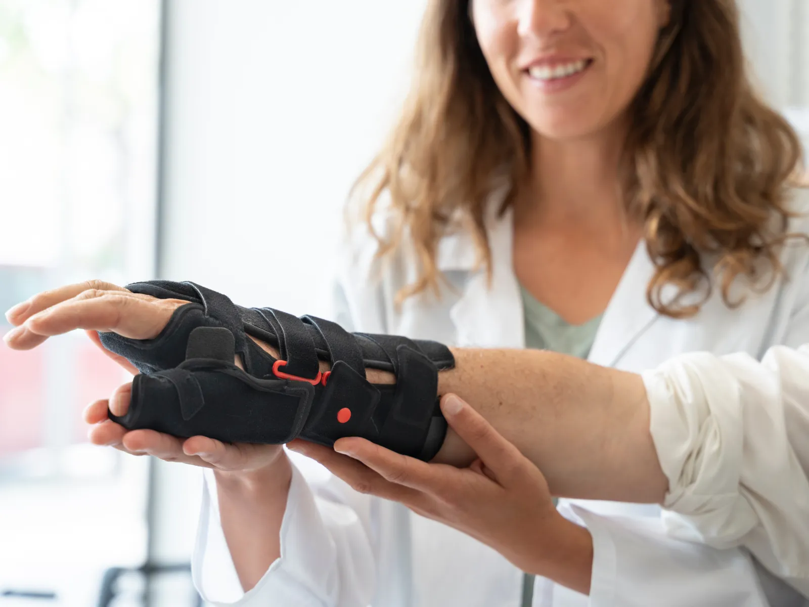 Doctor consulting male patient with knee pain and showing knee X-ray on monitor in medical clinic.