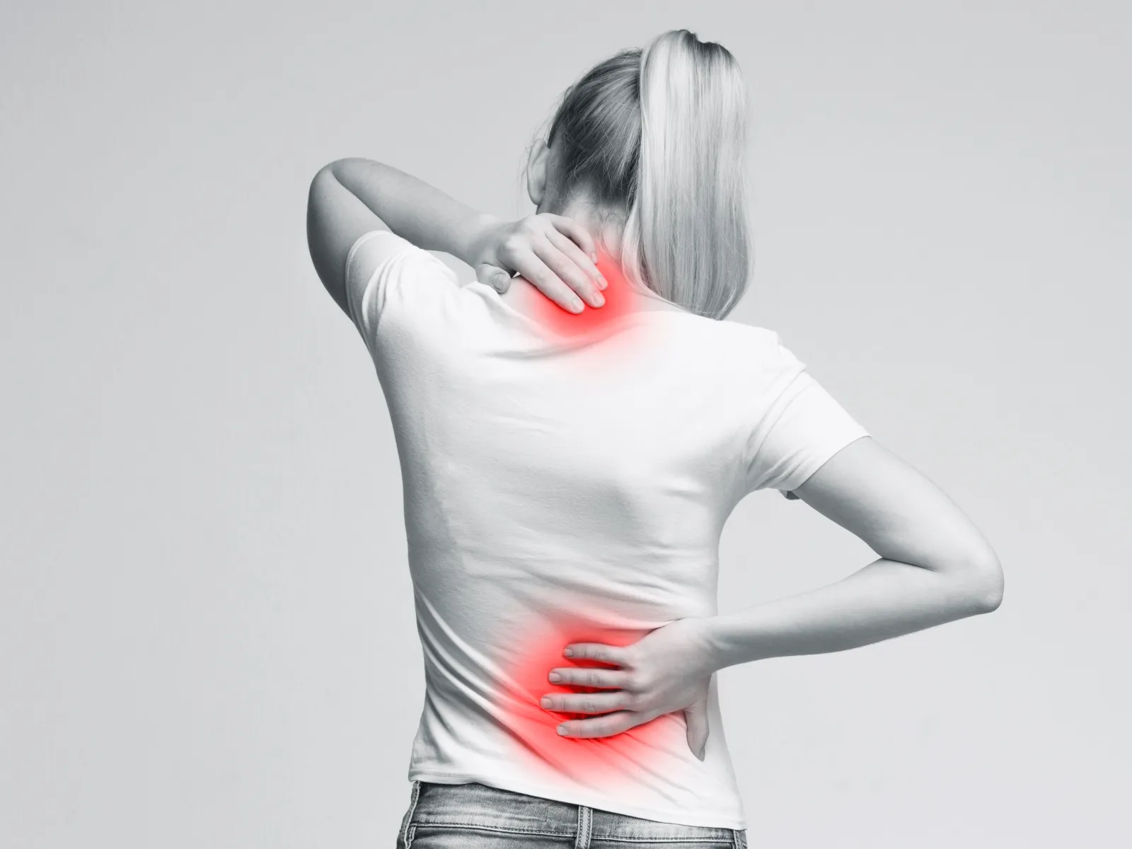 Woman holding neck and lower back with highlighted pain areas in red, indicating discomfort or injury.