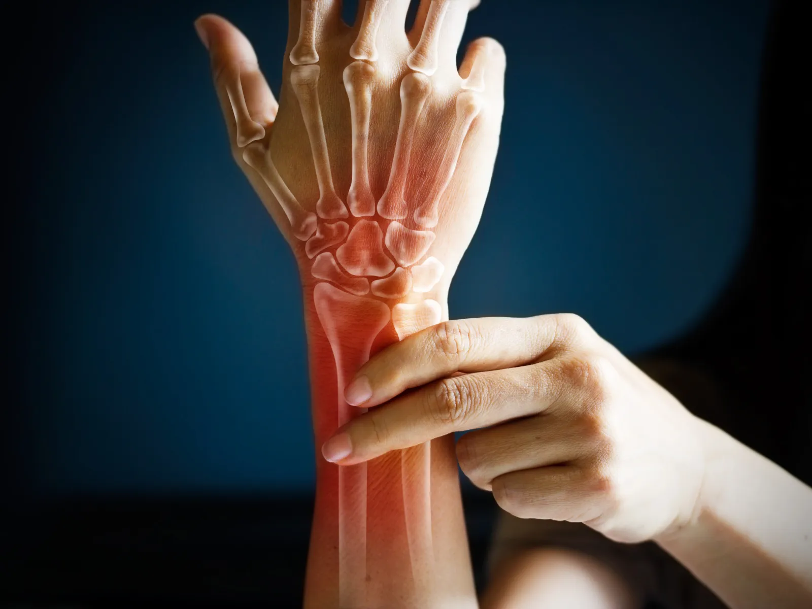 Human hand showing wrist pain with an X-ray overlay highlighting bones and inflammation in red.