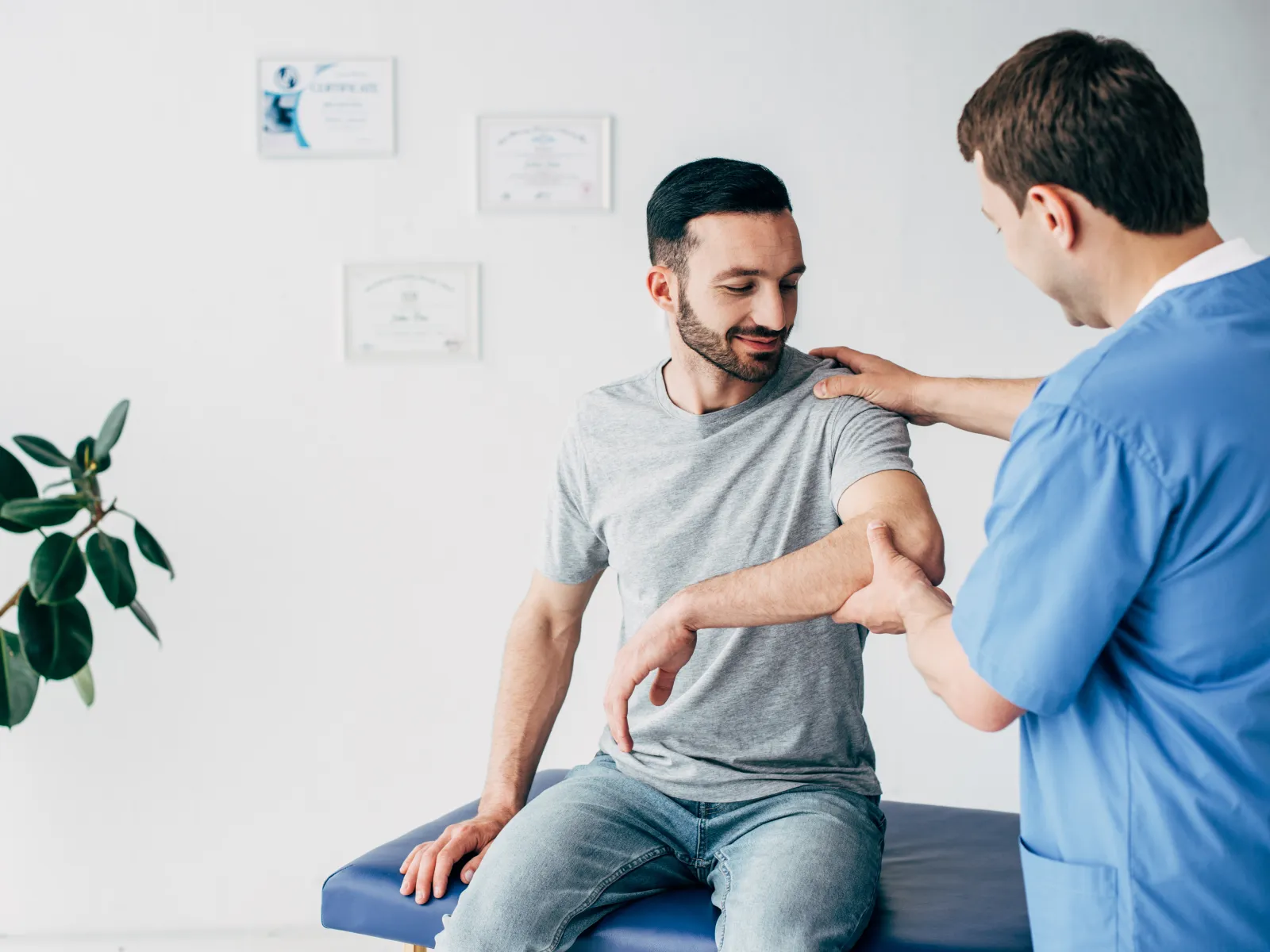 Physiotherapist examining and guiding a patient's arm movement during a physical therapy session in a clinic