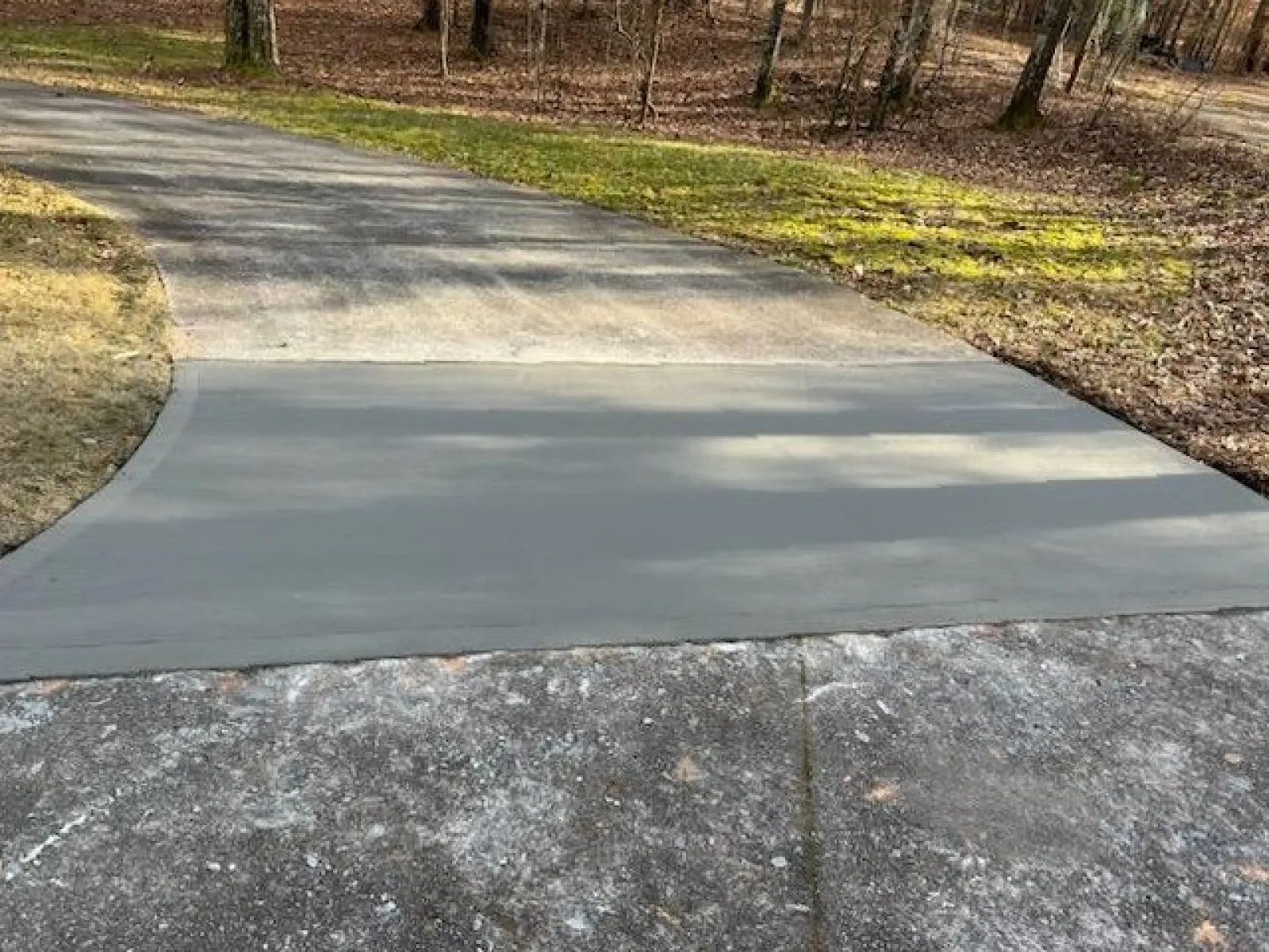 a paved path with grass and trees