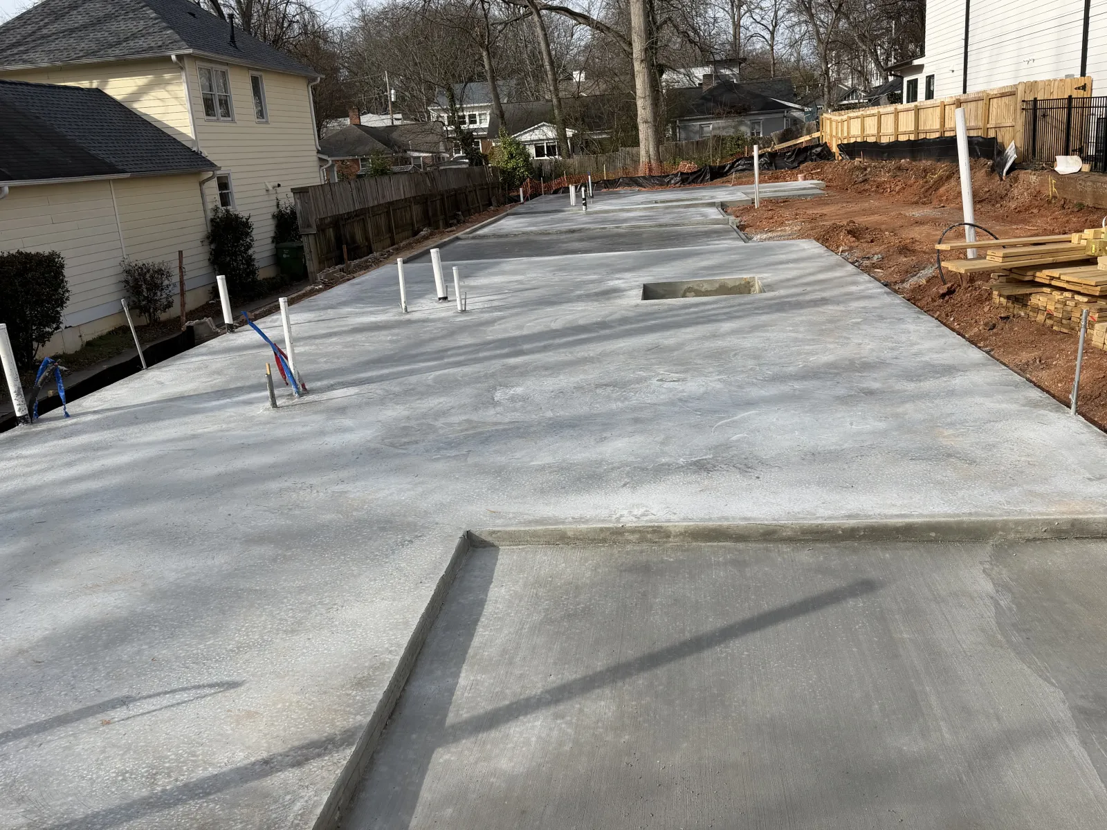 New concrete foundation slab with plumbing pipes set for residential home construction.