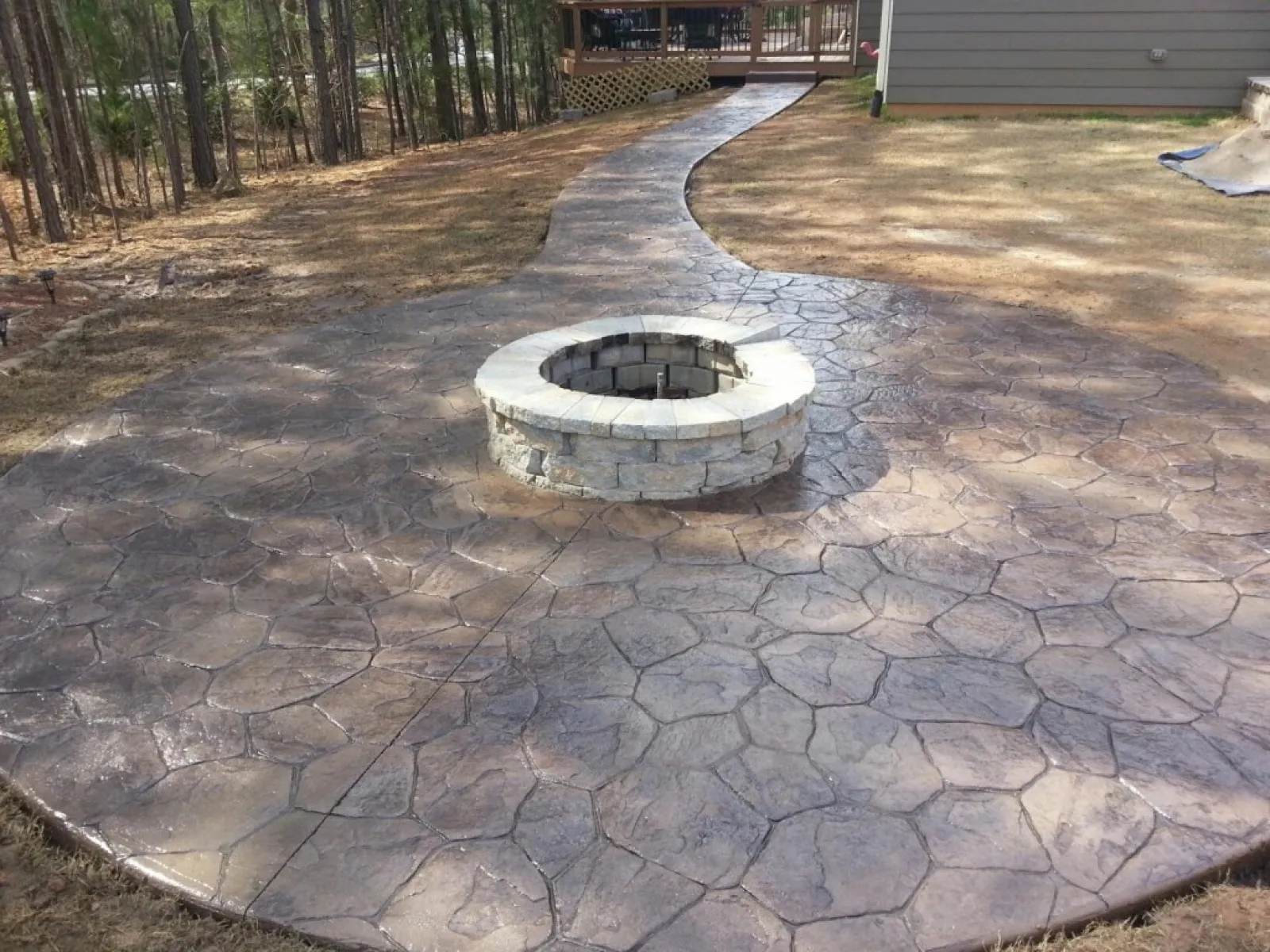 Beautifully designed stone patio with a circular fire pit surrounded by patterned concrete.