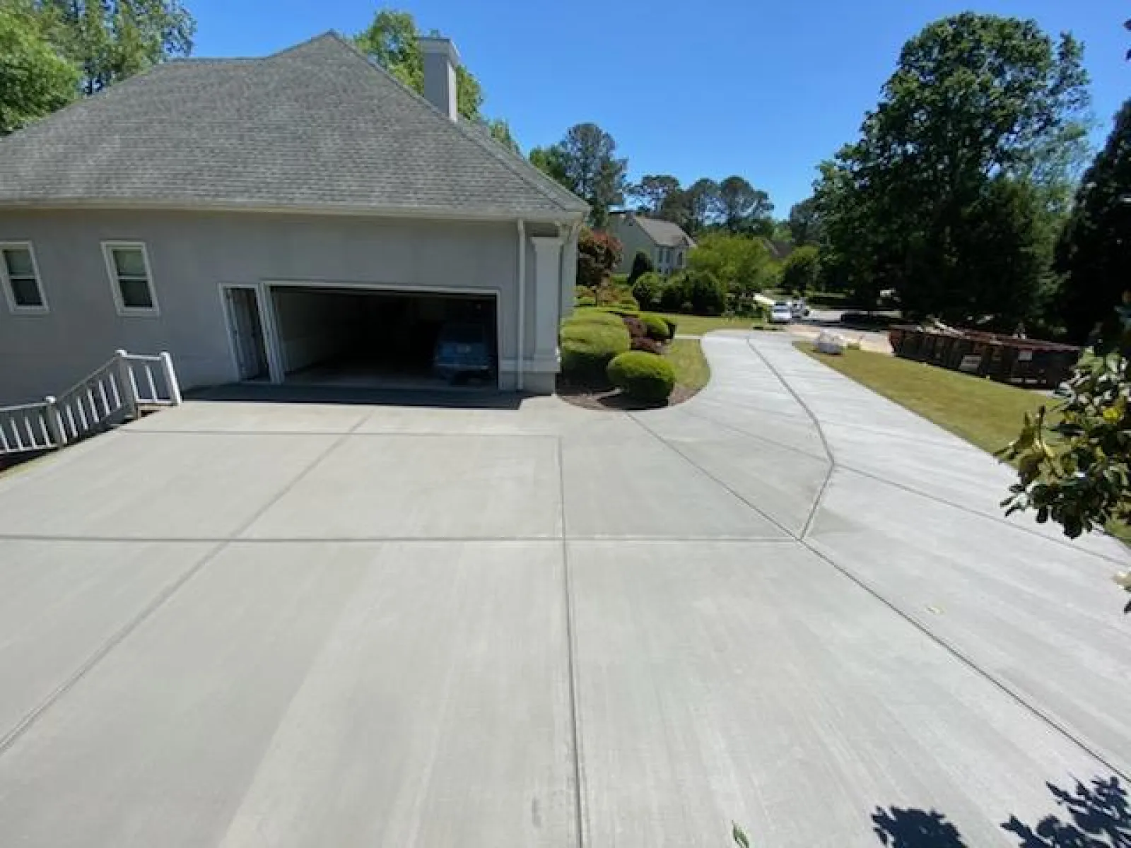 Newly poured clean concrete driveway leading to a residential garage on a sunny day.