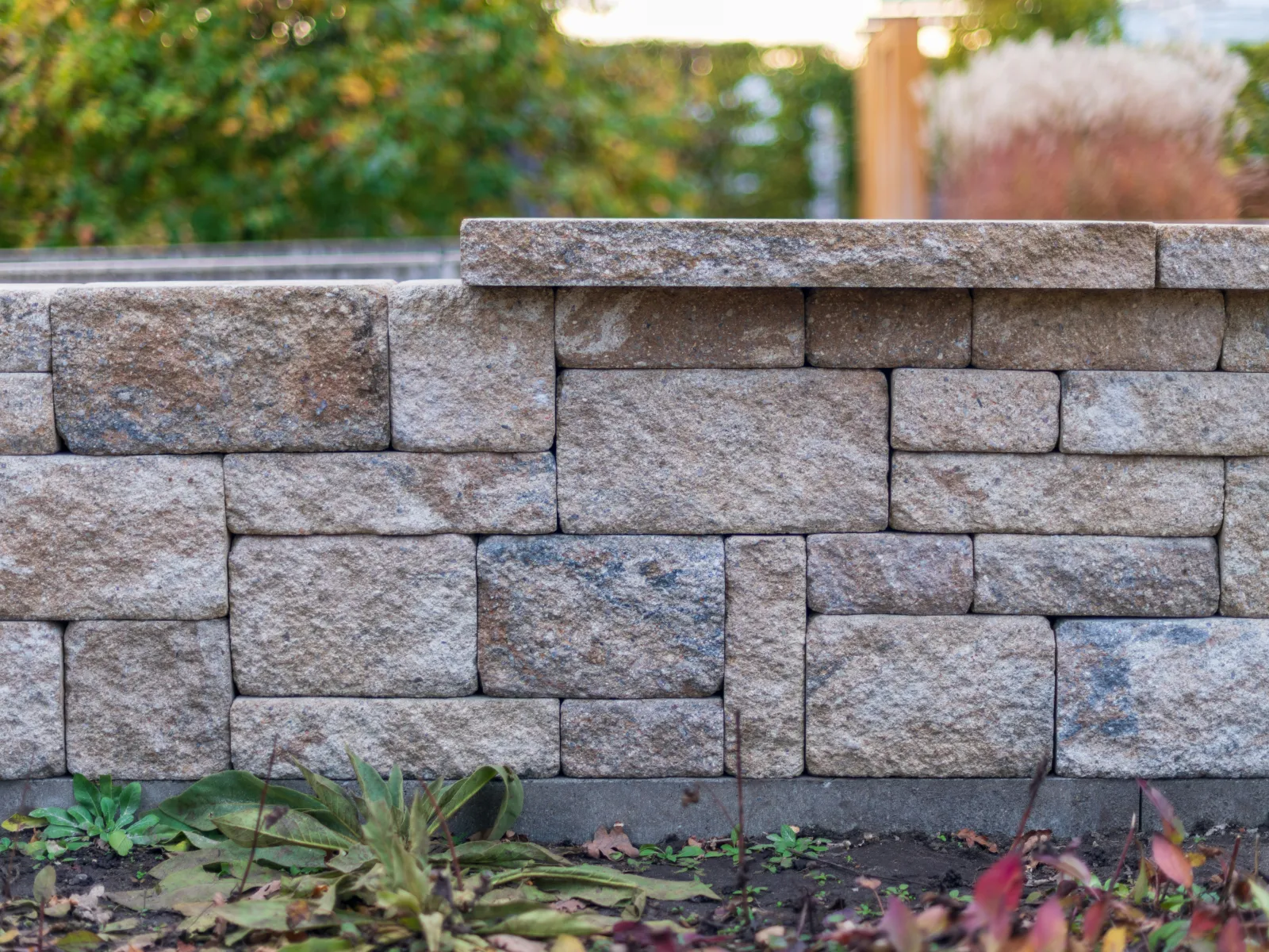 Decorative garden retaining wall built with stacked natural stone blocks in neutral tones outdoors.