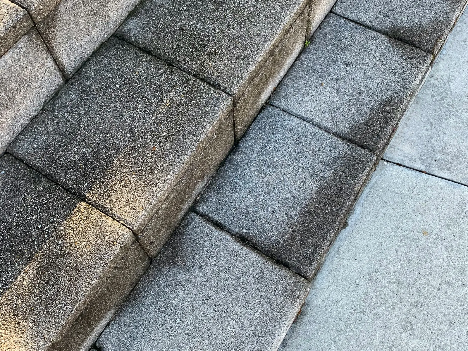 Close-up of textured concrete steps and adjacent sidewalk after cleaning, showing contrast between clean and dirty areas.