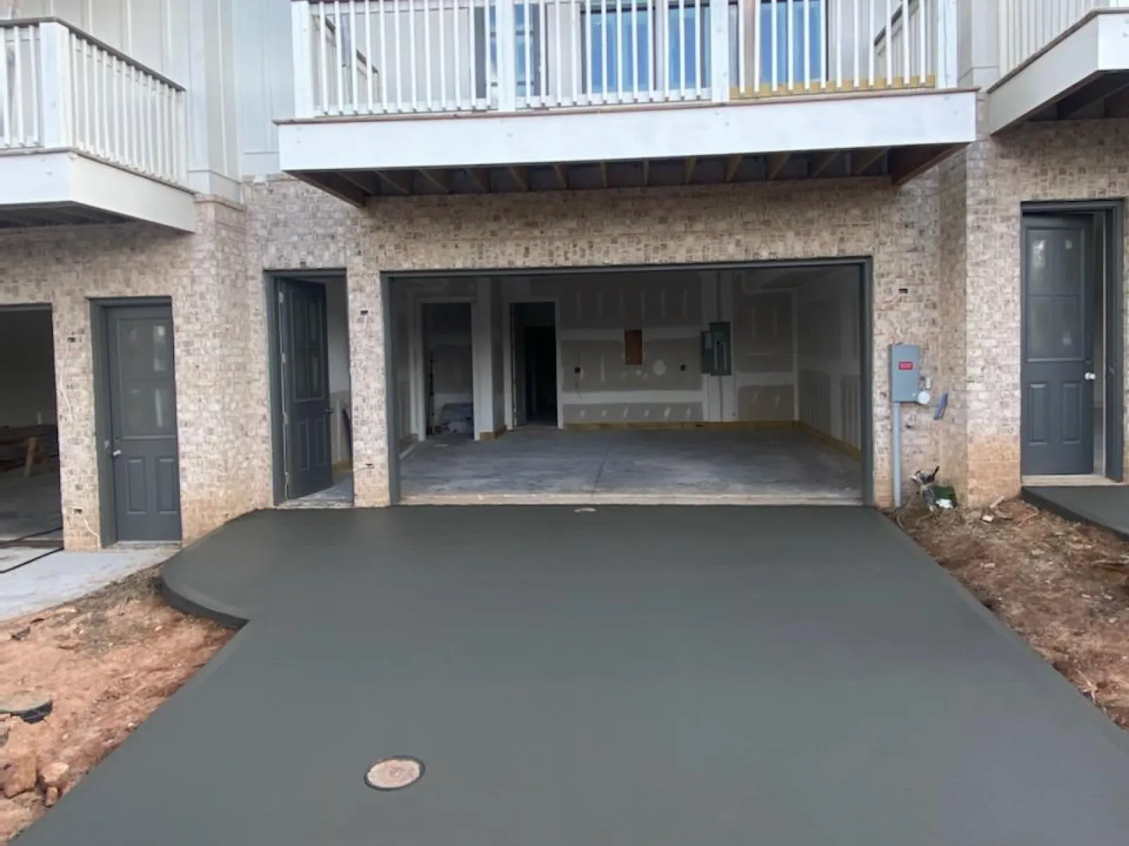 Freshly poured concrete driveway in front of a newly constructed house with a balcony.