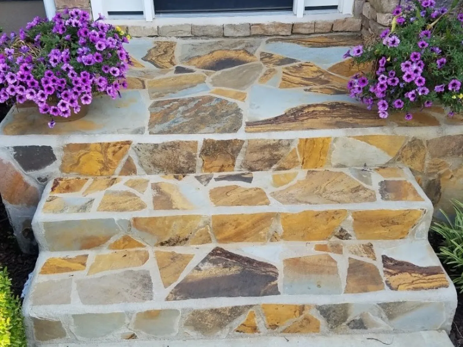 a stone wall with a door and a flower pot
