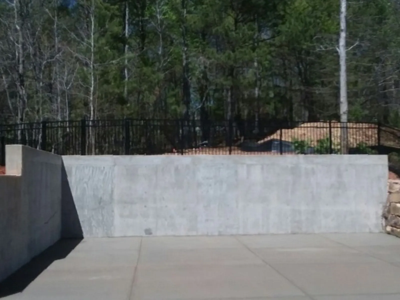 a concrete wall with a fence and trees in the background