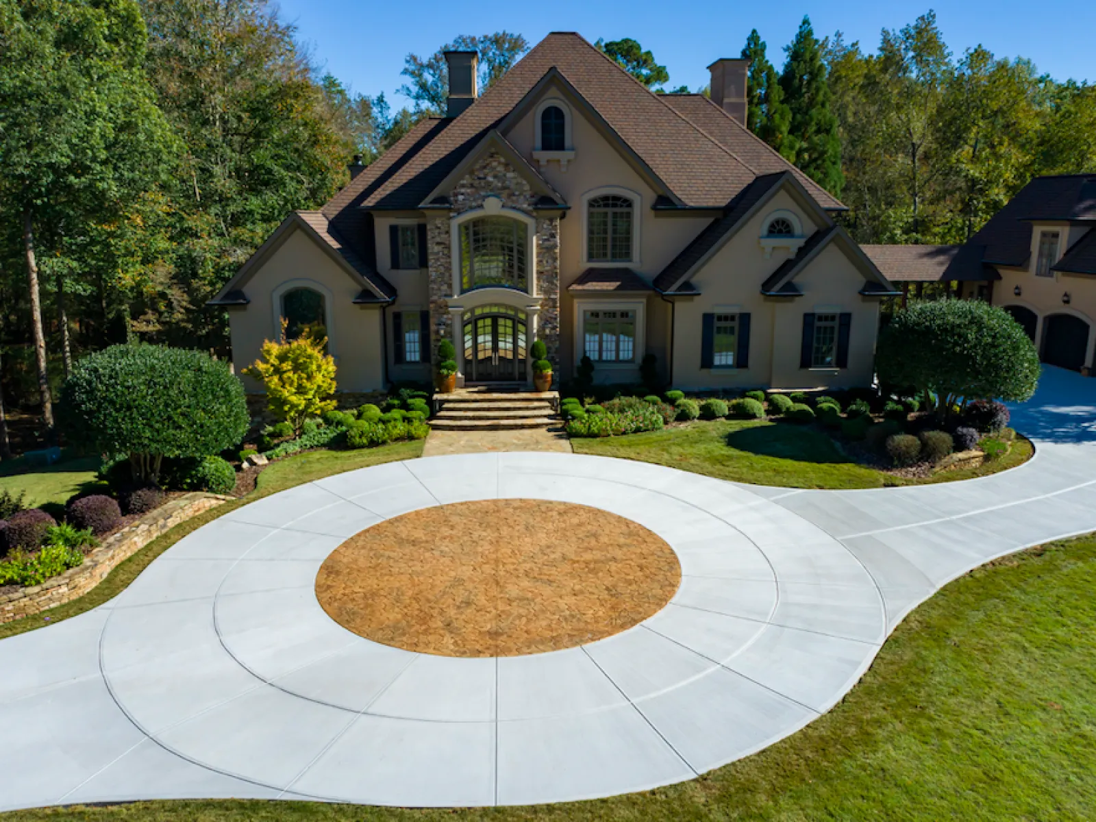 Elegant large home with beautifully landscaped front yard and unique circular driveway design.