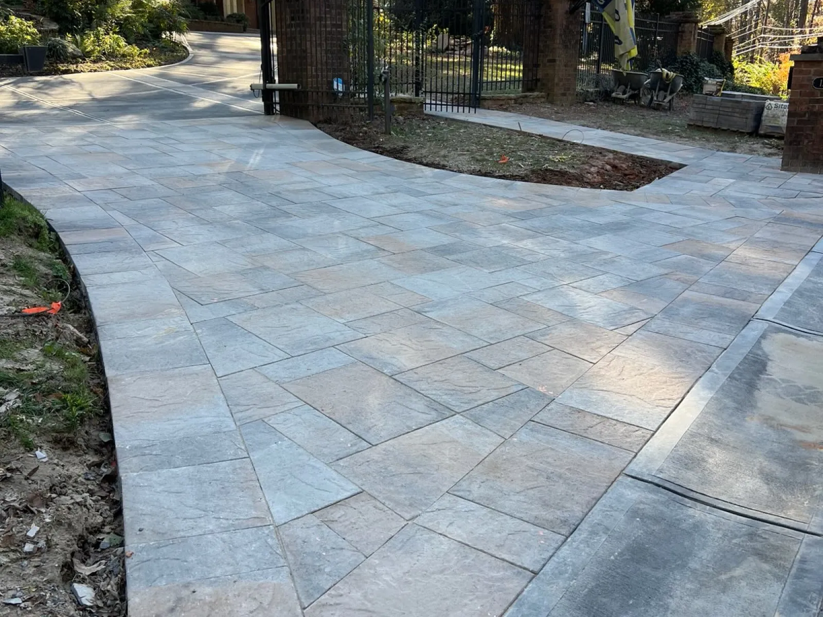 a stone walkway with a fence and trees on the side