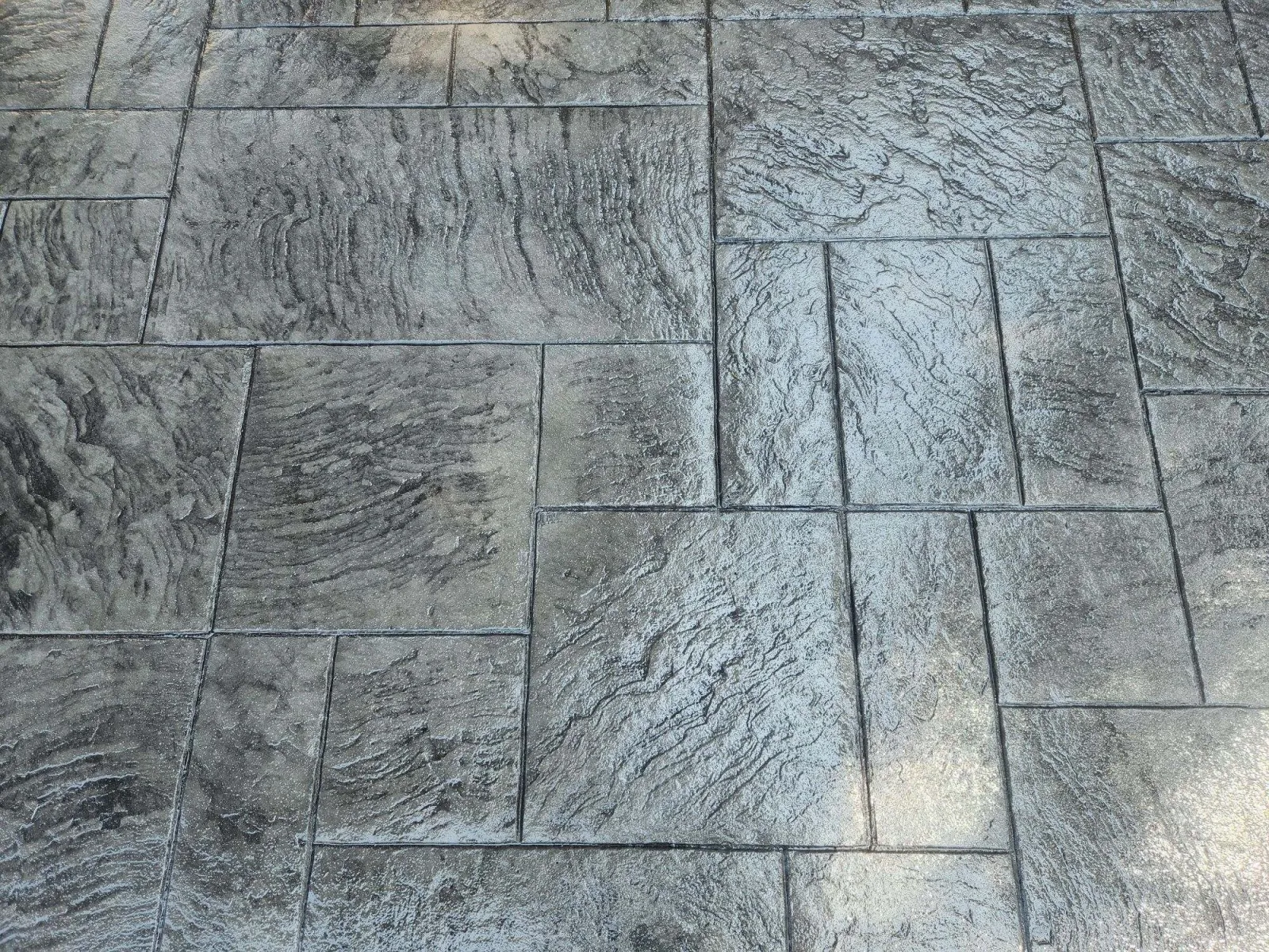 Textured gray stamped concrete floor tiles with a natural stone appearance.