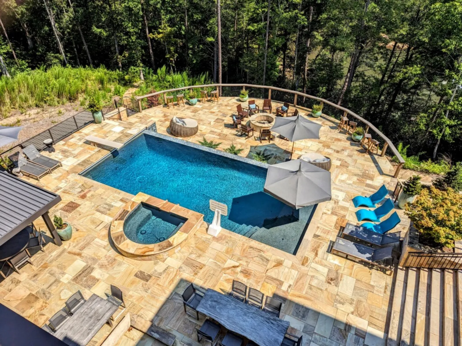 Aerial view of a luxurious backyard with a pool, spa, patio, and lush greenery.