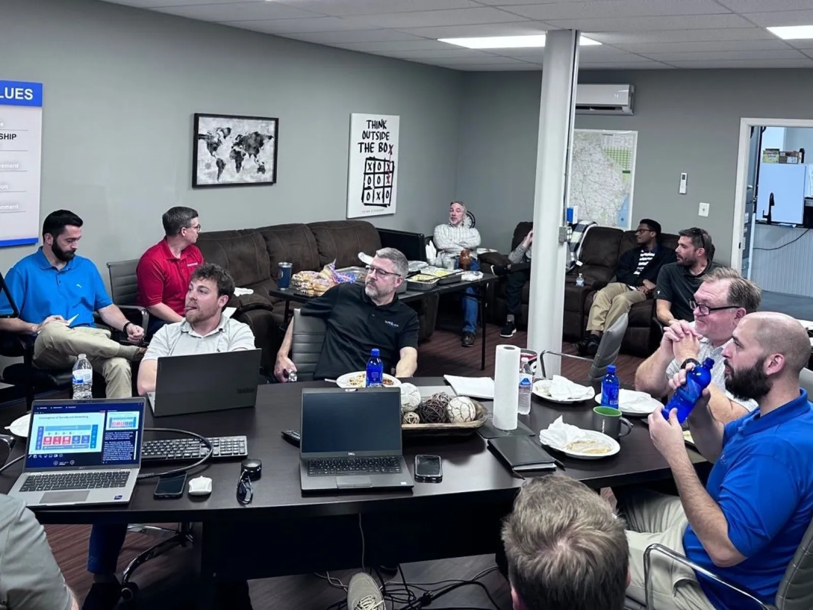 a group of people sitting around a table with laptops