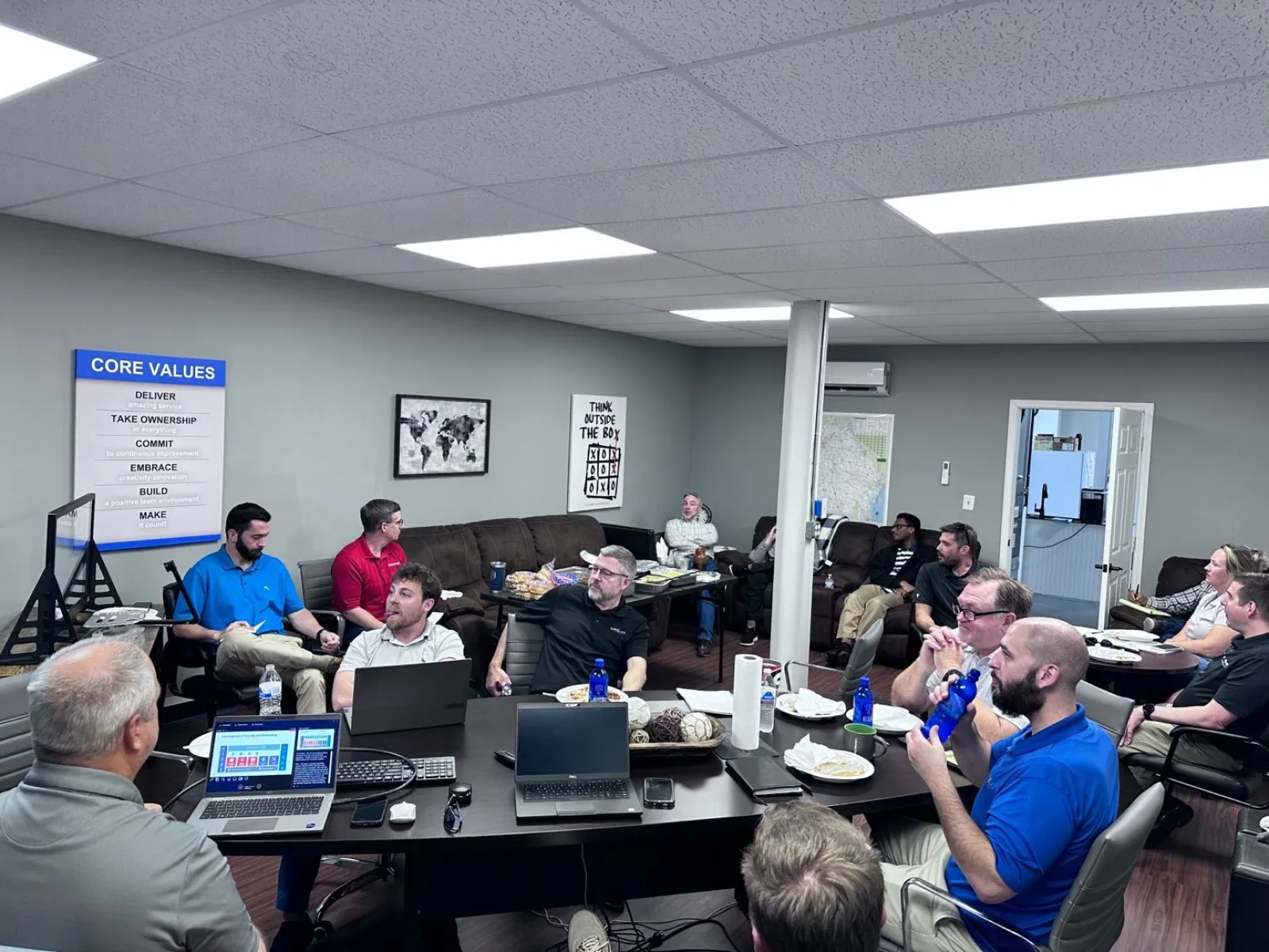 a group of people sitting around a table with laptops